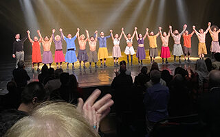 Dancers taking a bow on stage, audience clapping