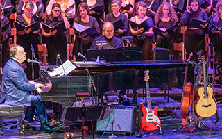 Rob Mathes playing piano with chorus