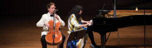 David Finckel in white jacket playing cello and Wun Han in a bright colorful blouse playing piano