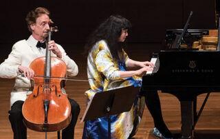 David Finckel in white jacket playing cello and Wun Han in a bright colorful blouse playing piano