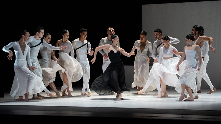 Ballet Hispanico's Carmen. Female dancer in black costume surrounded by dancers in white.