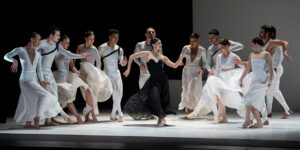 Ballet Hispanico's Carmen. Female dancer in black costume surrounded by dancers in white.